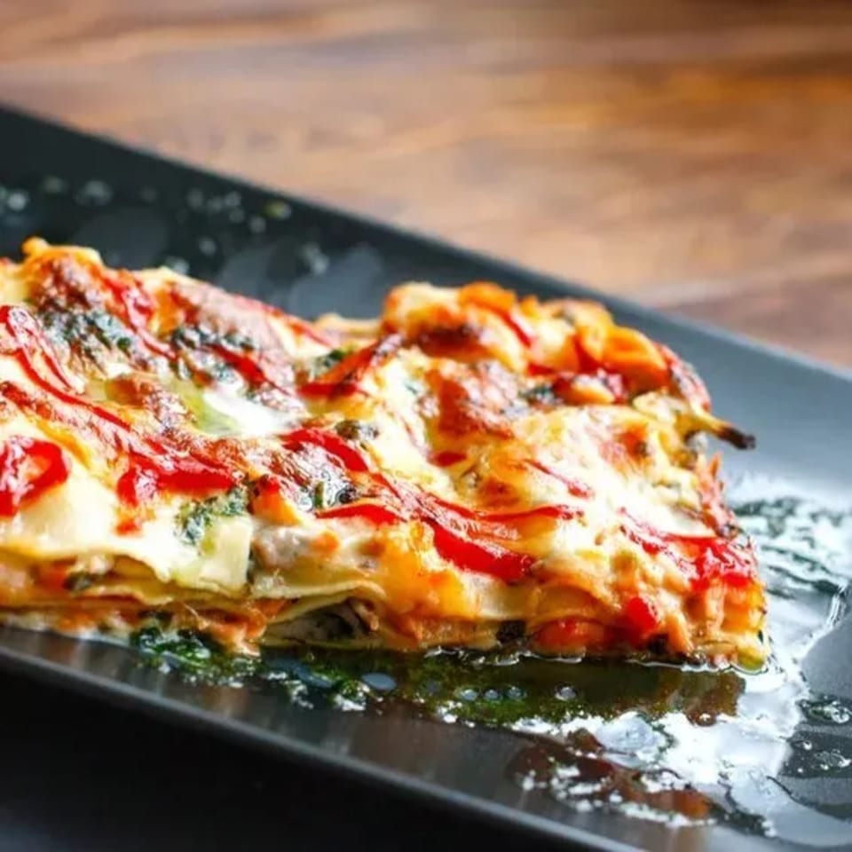 A delicious slice of Sali's Pizza & Pasta lasagna with melted cheese and red sauce.